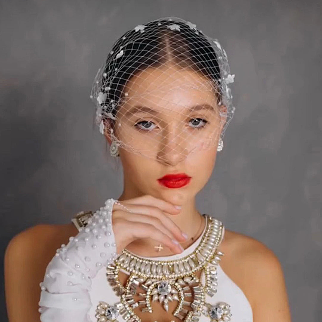 Woman wearing a decorative headpiece and jewelry against a gray background