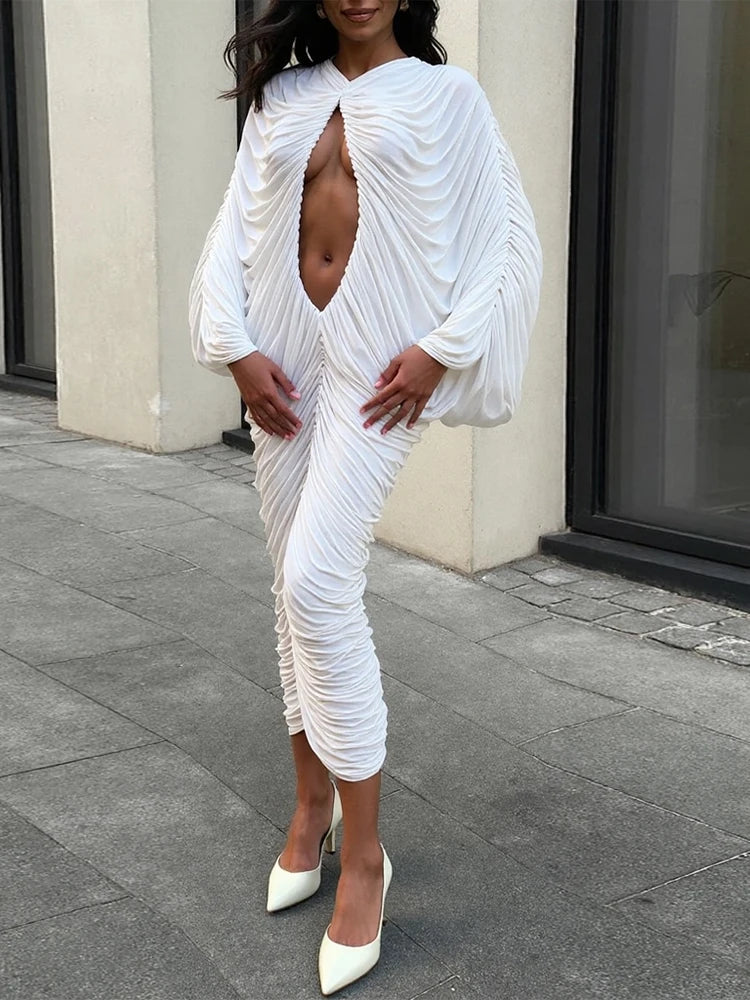 Woman wearing a white ruched dress with a low neckline on a city street.
