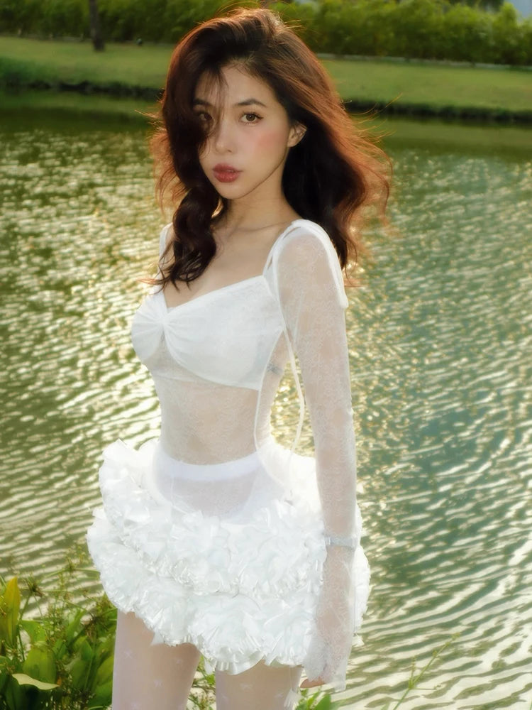 Woman in a white dress standing by a body of water with greenery in the background