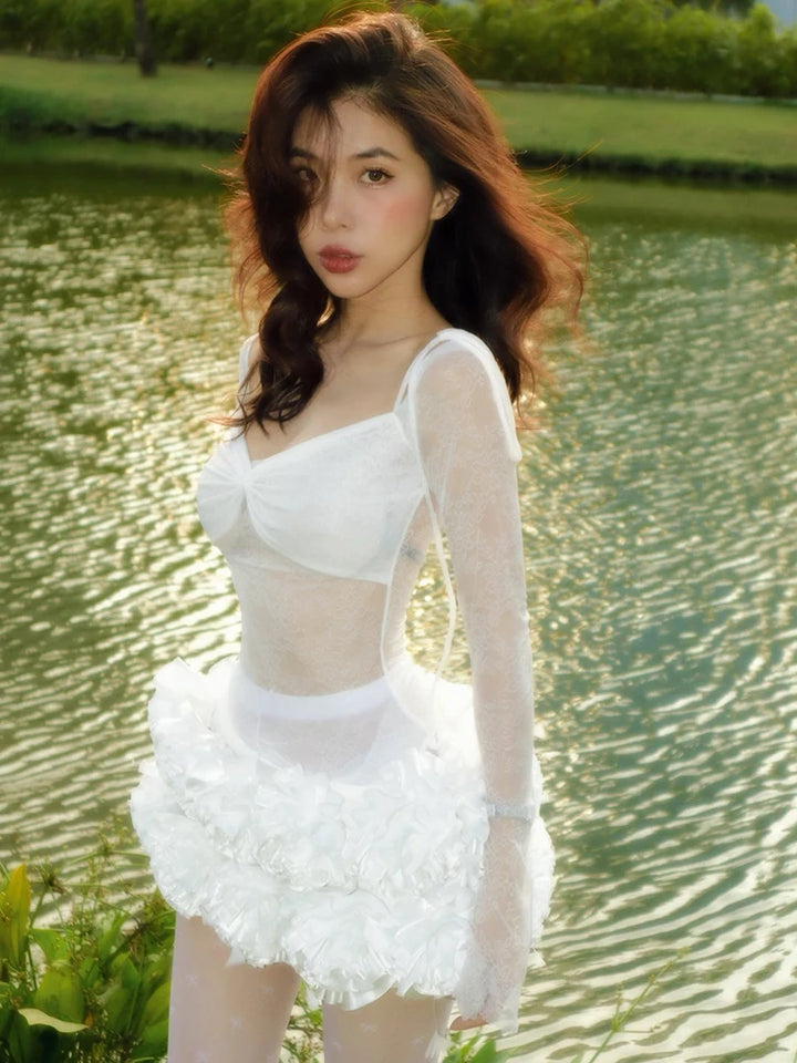 Woman in a white dress standing by a body of water with greenery in the background