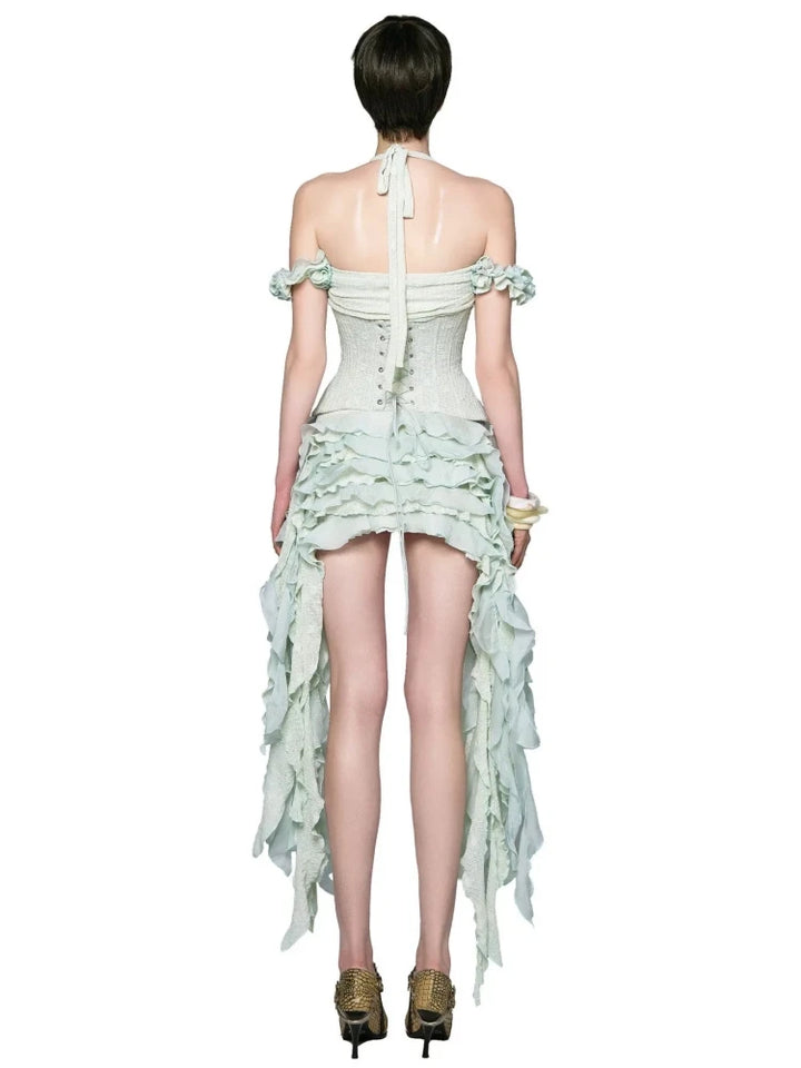 Woman wearing a light green dress with ruffled details on a white background