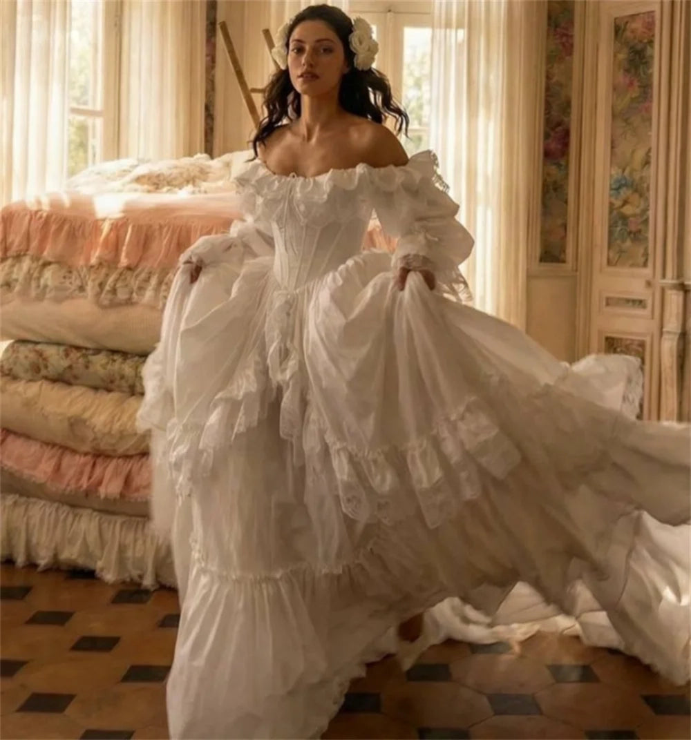 Woman in a white, elaborate gown standing in a room with floral decorations.