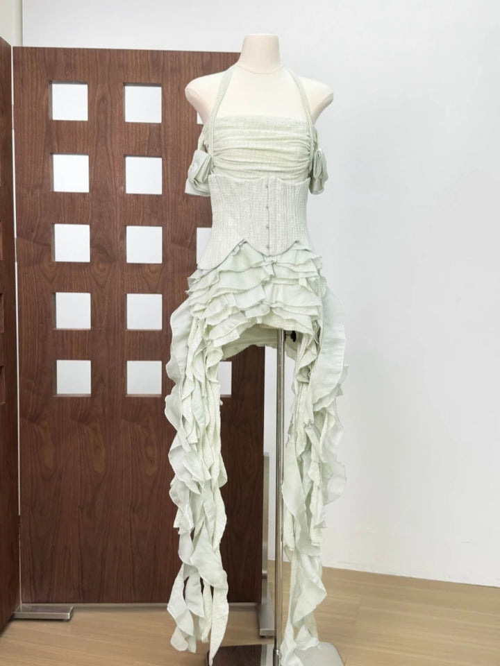 Mannequin wearing a white, ruffled dress against a plain wall.