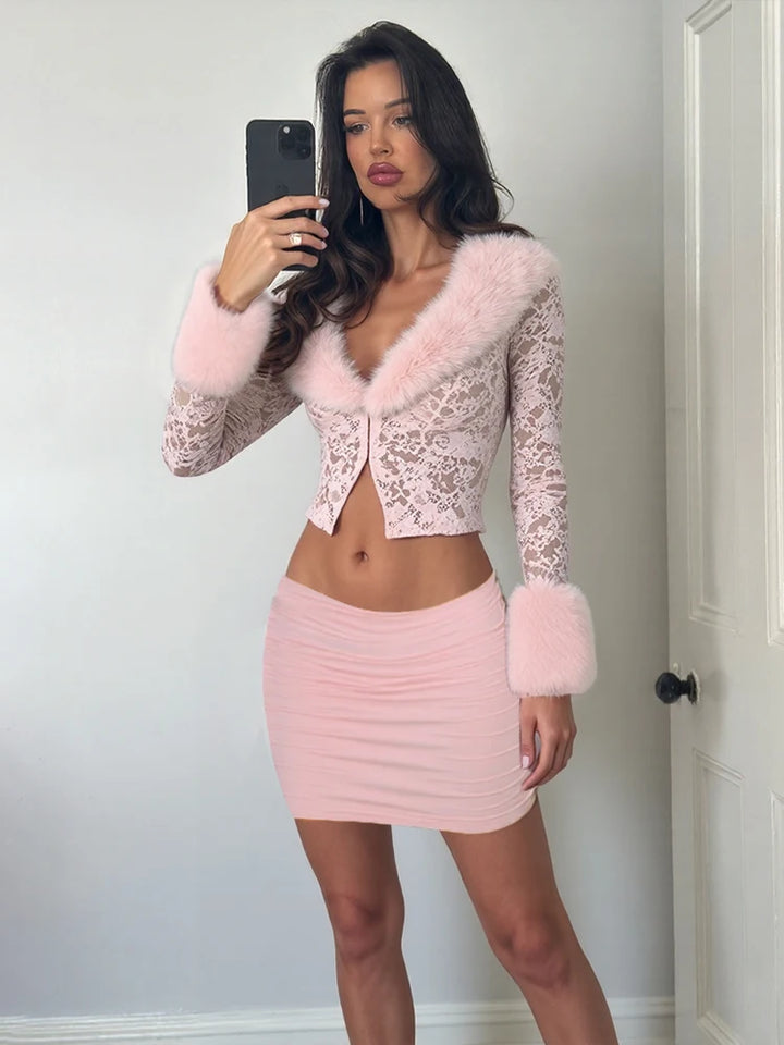 Woman wearing a pink lace top with fur trim and matching skirt, taking a mirror selfie.