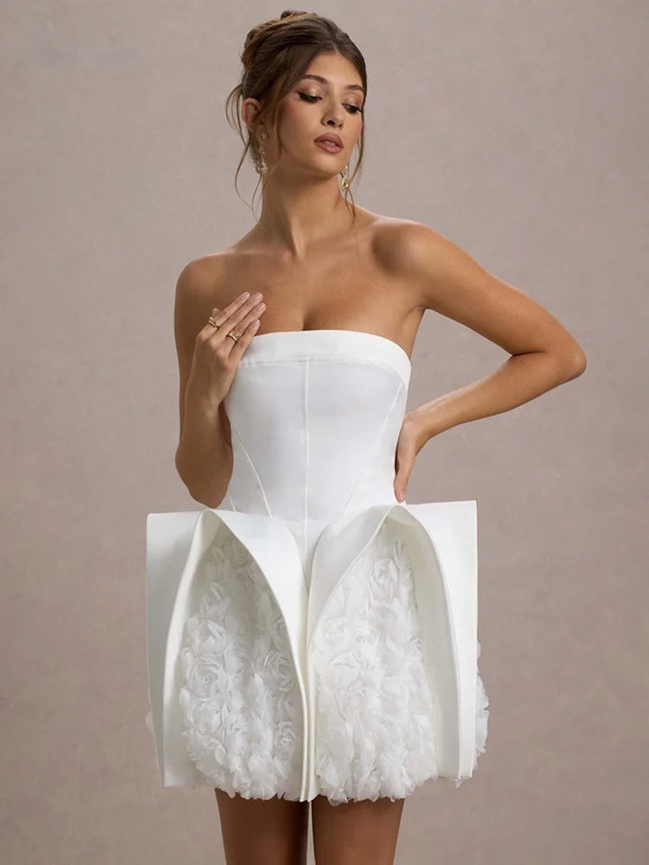 Woman wearing a white strapless dress with a unique skirt design on a beige background