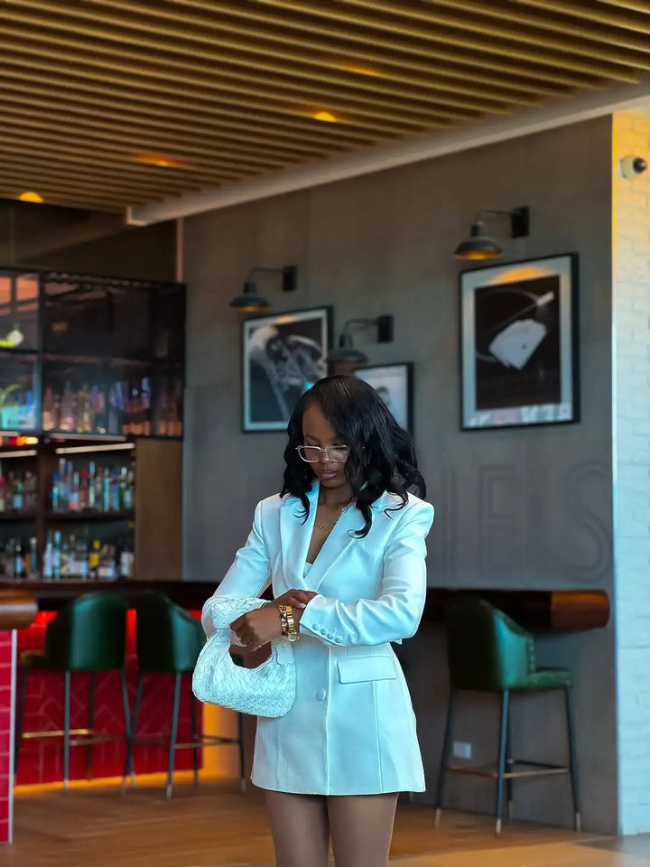 Woman in a light blue blazer standing in a bar setting