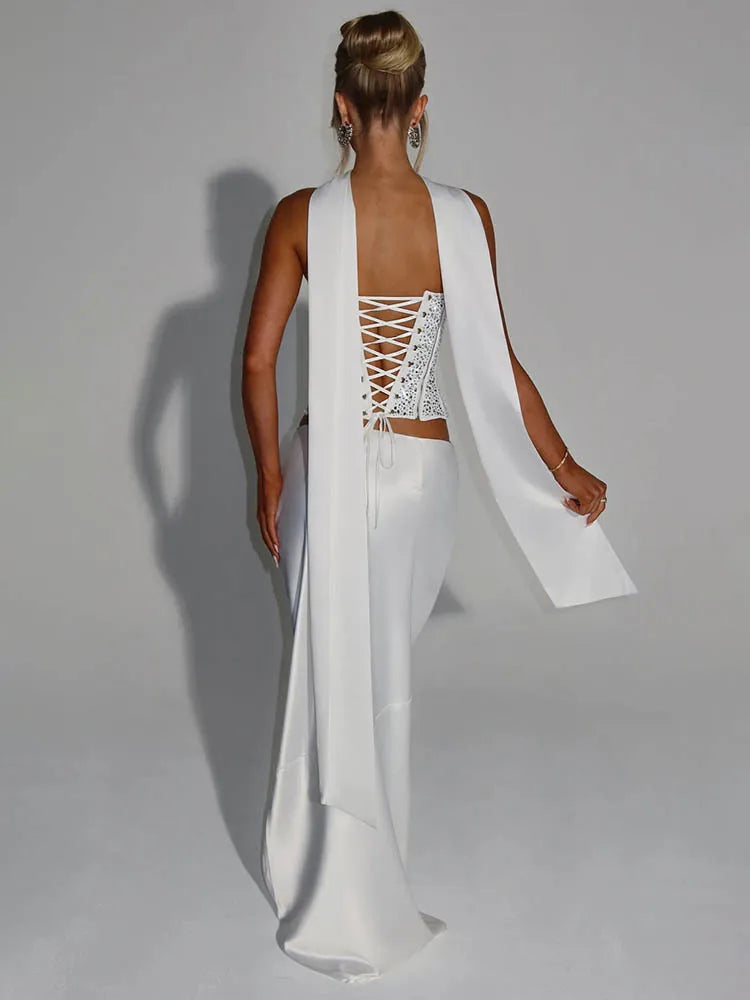 White dress with a lace-up back and flowing fabric on a plain background