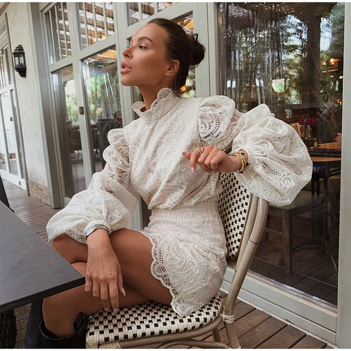 Woman in a white lace dress sitting at an outdoor cafe.