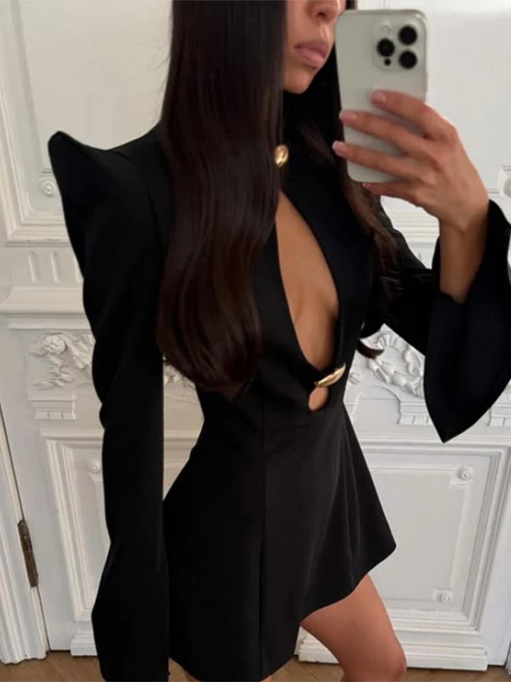 Person wearing a black dress with cut-out design in front of a decorative wall.