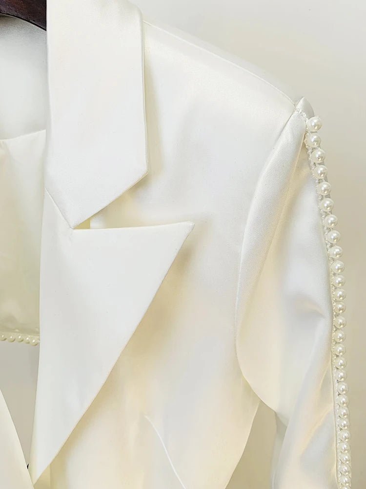 Close-up of a white fabric with a textured pattern and pearl trim.