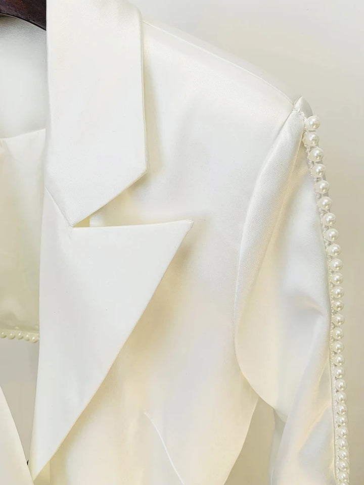 Close-up of a white fabric with a textured pattern and pearl trim.