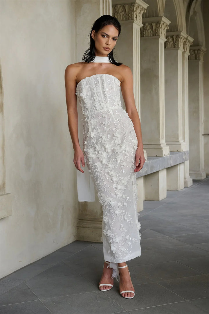 Woman in a strapless white lace dress standing in an architectural setting.