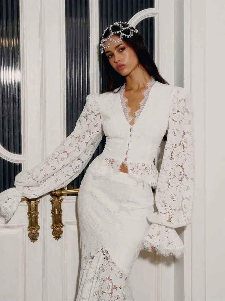Woman in a white lace outfit standing against a decorative door.