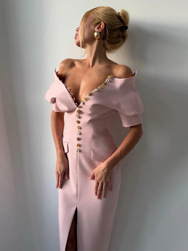 Woman wearing a pink off-shoulder dress with gold buttons against a plain background