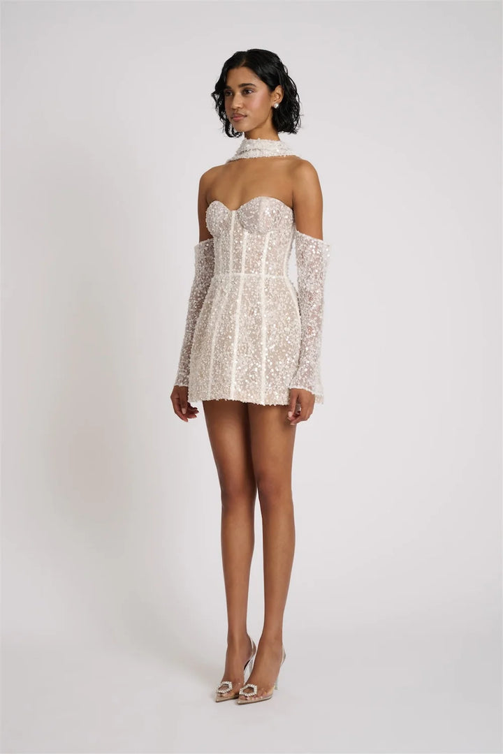 Woman wearing a white lace dress with thin straps on a plain background