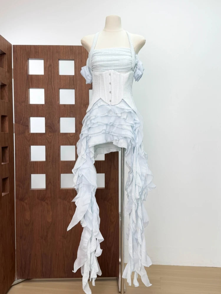 White ruffled dress on a mannequin against a wooden door and white wall.