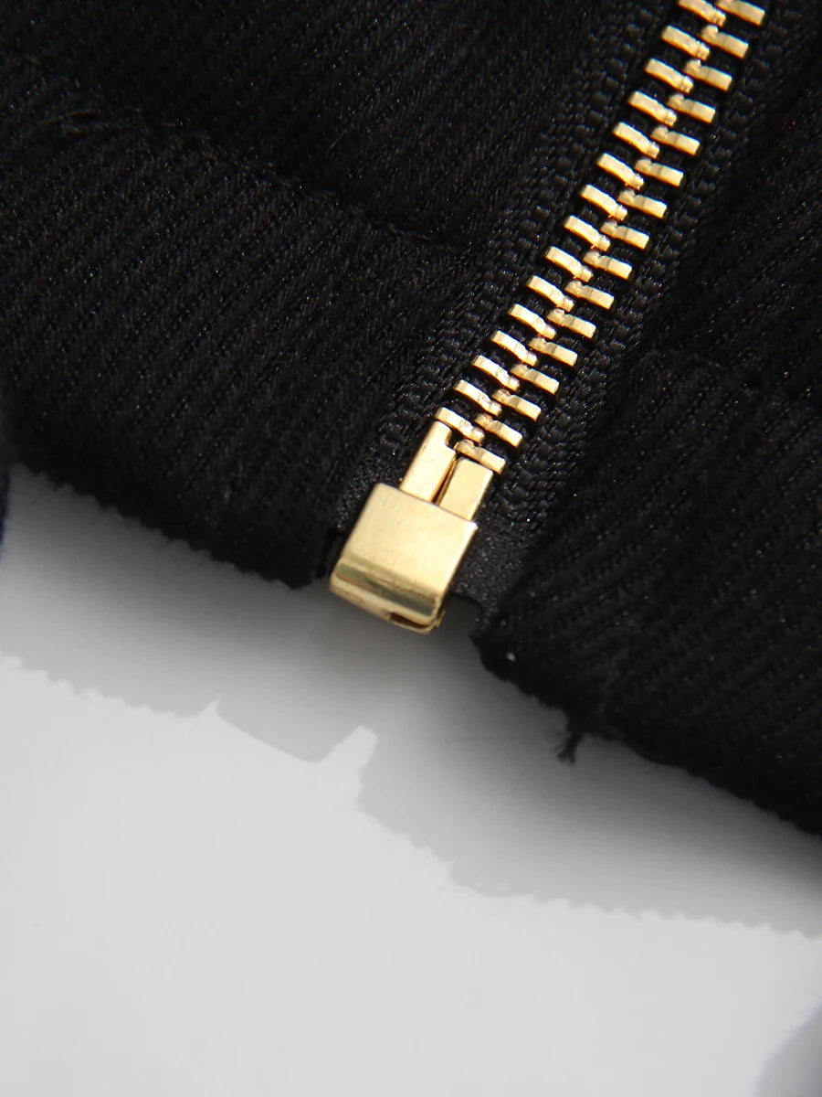 Close-up of a black fabric with a gold zipper on a white background