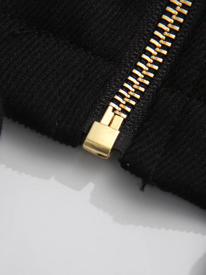 Close-up of a black fabric with a gold zipper on a white background
