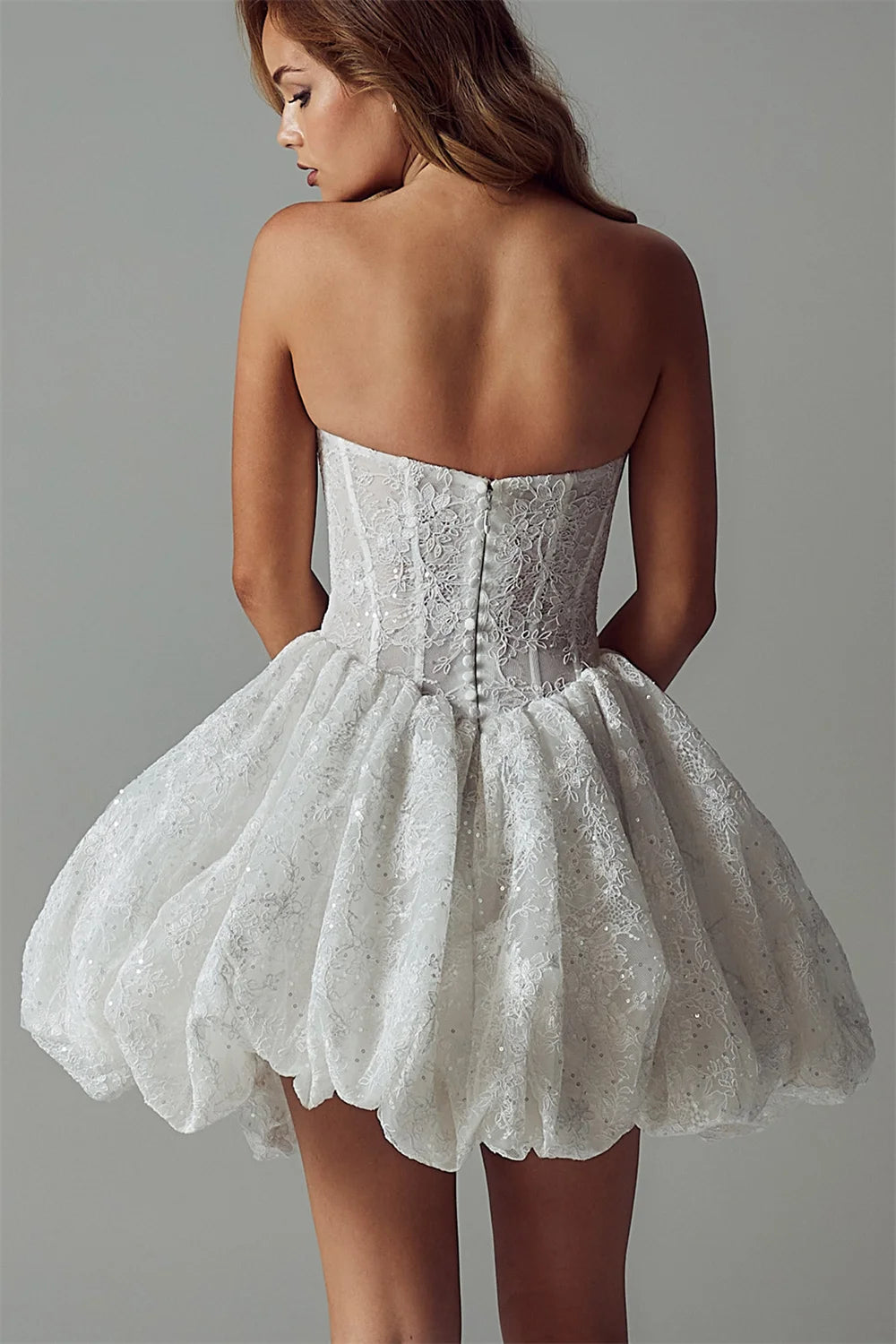 White lace dress worn by a model on a gray background