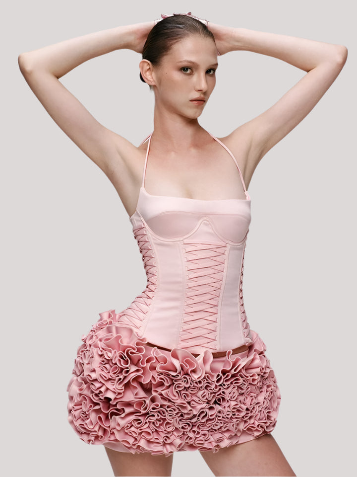 Model wearing a pink corset dress with floral details on a plain background