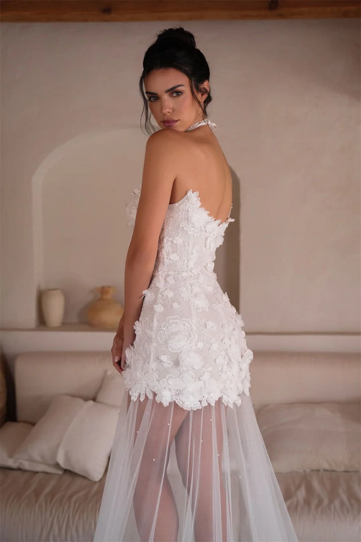 Woman wearing a white floral dress in a softly lit room.