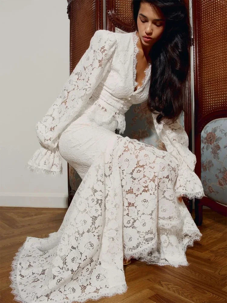 Woman wearing a white lace outfit sitting on a wooden floor.
