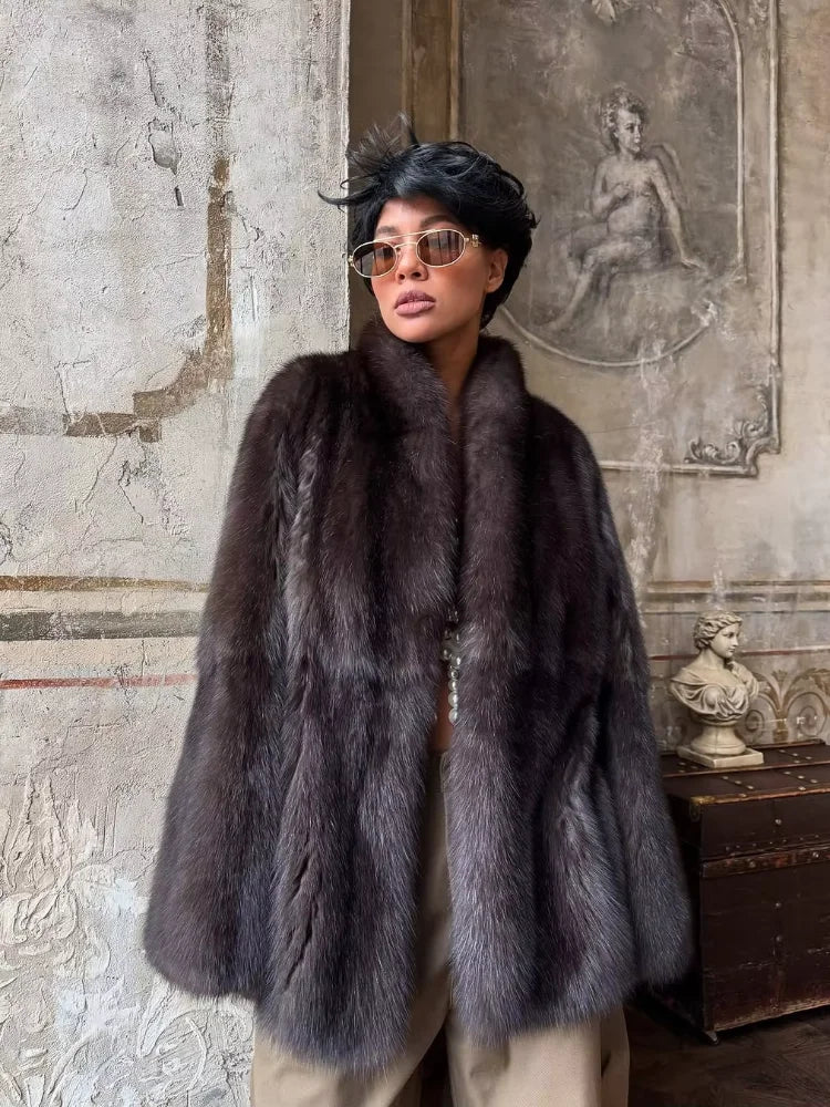 Person wearing a fur coat in an ornate room with classical art on the wall.
