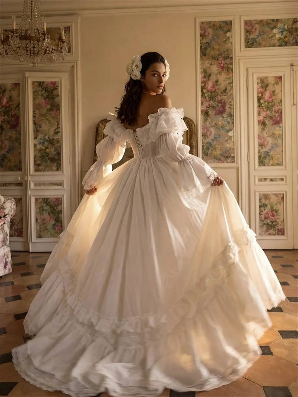 Woman in a white wedding dress standing in an ornate room with floral decorations.