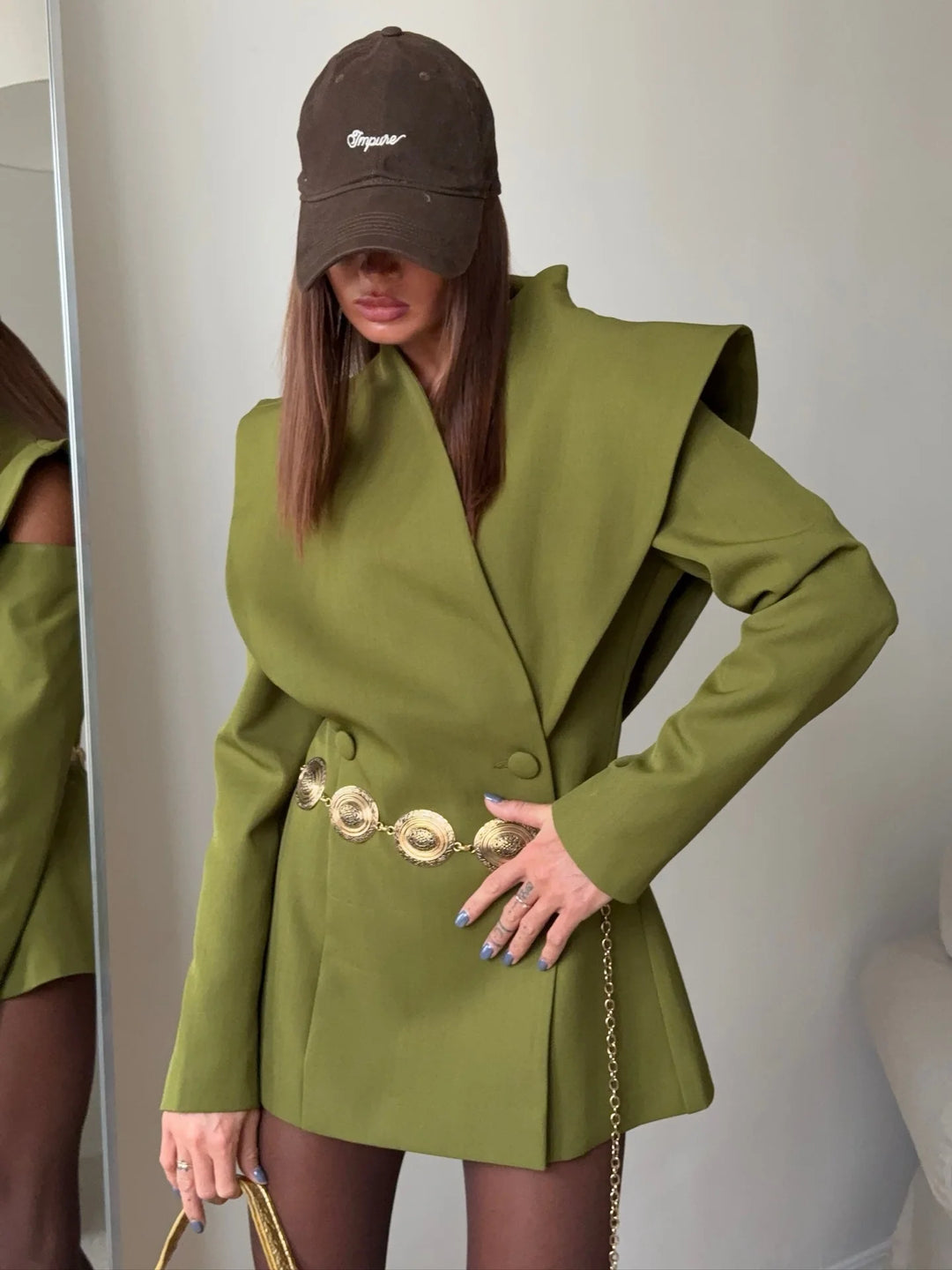 Person wearing a green coat and brown cap indoors