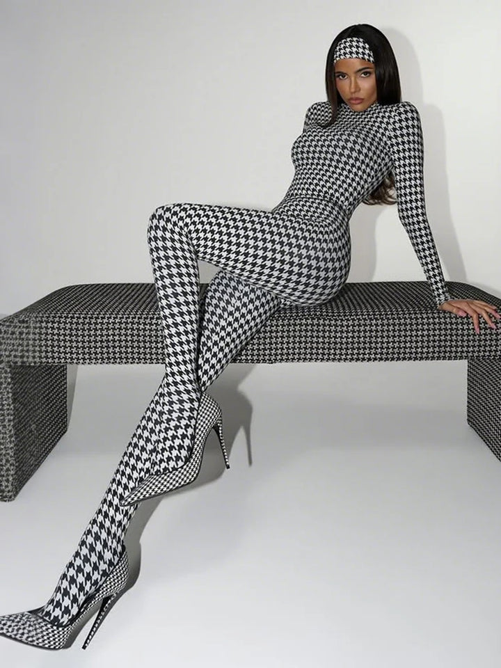 Person wearing a black and white checkered outfit sitting on a bench.