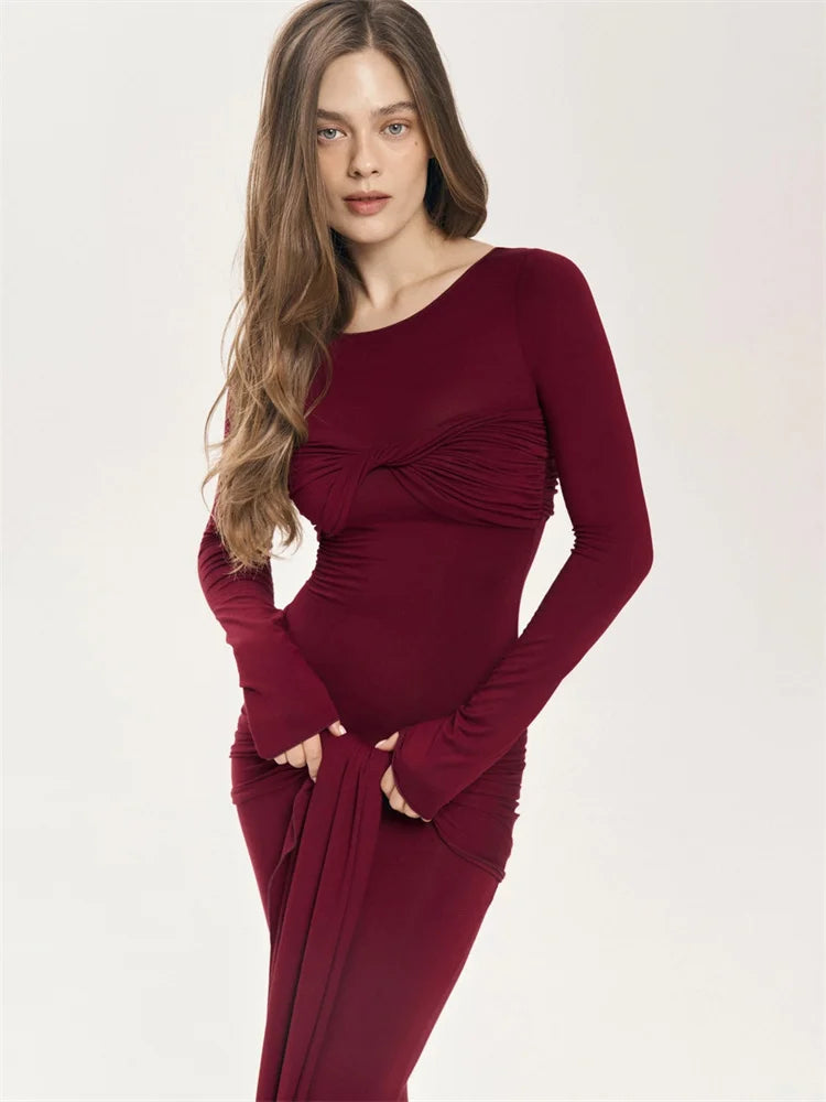 A woman wearing a red maxi dress with pleated detailing and a crew neckline.