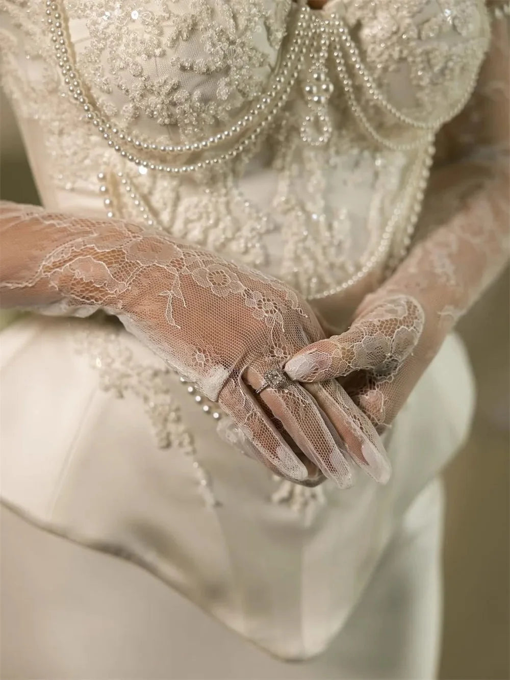 Close-up of a hand wearing a lace glove with a detailed dress in the background