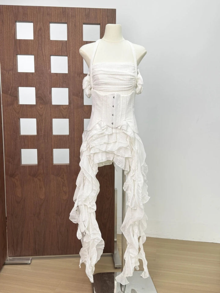 Mannequin wearing a white dress with ruffled details against a wooden panel background