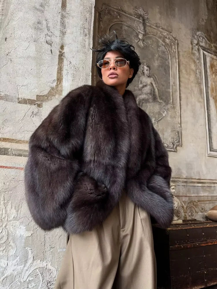 Person wearing a dark fur coat in an ornate interior setting