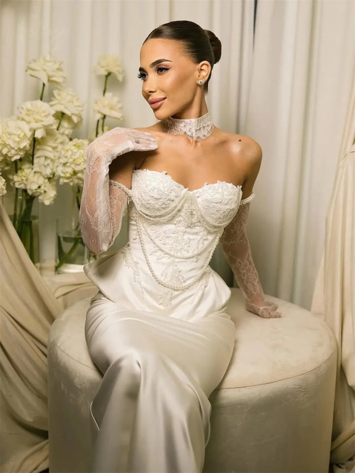 Woman in a white wedding dress sitting on a chair with flowers in the background