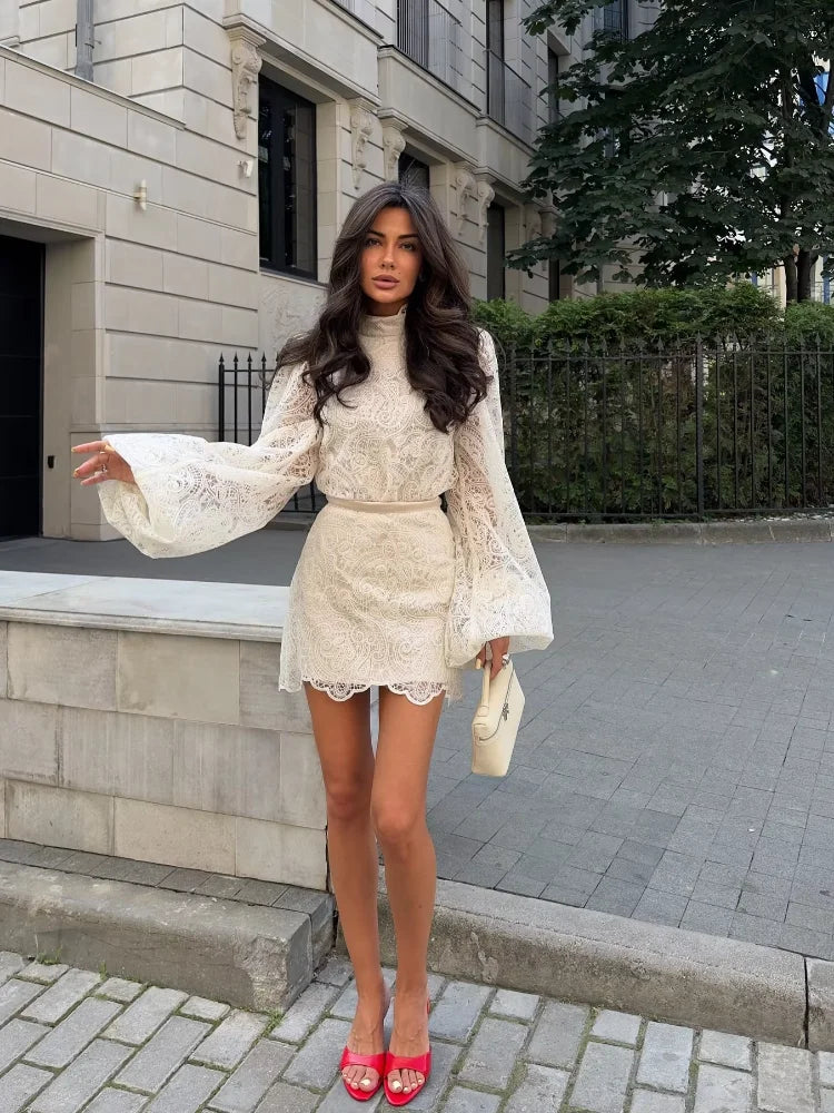 Woman in a white lace outfit standing on a street.