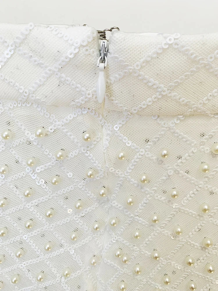 Close-up of a white textured fabric with pearl-like beads and a zipper.