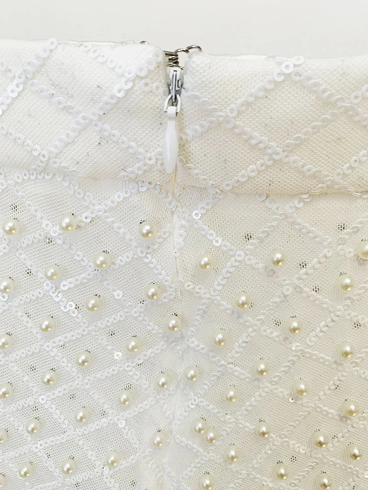 Close-up of a white textured fabric with pearl-like beads and a zipper.