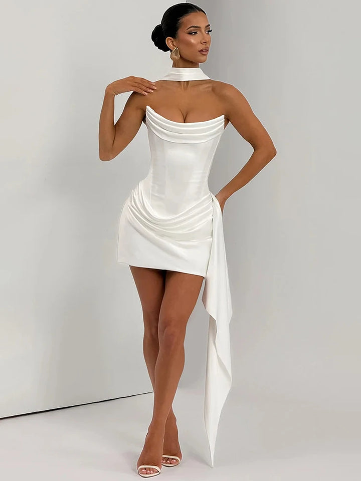 Woman wearing a white dress with a draped design on a plain background