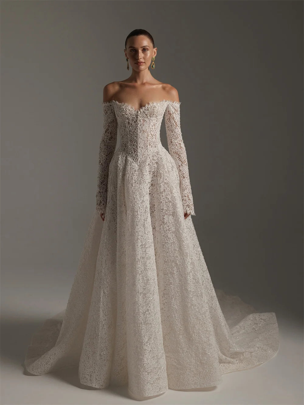 Woman wearing a white lace wedding dress against a gray background
