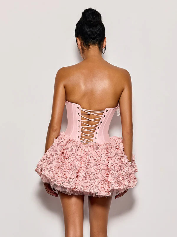 Pink strapless dress with floral skirt on a plain background