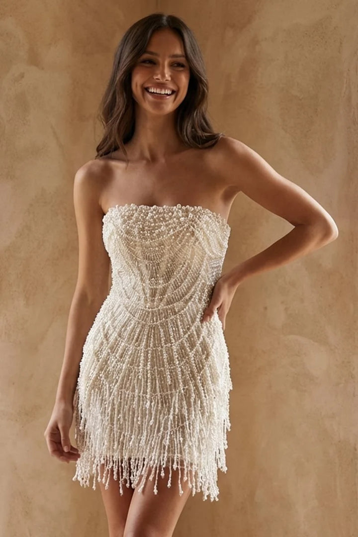 Woman wearing a strapless, beaded dress with fringe on a beige background