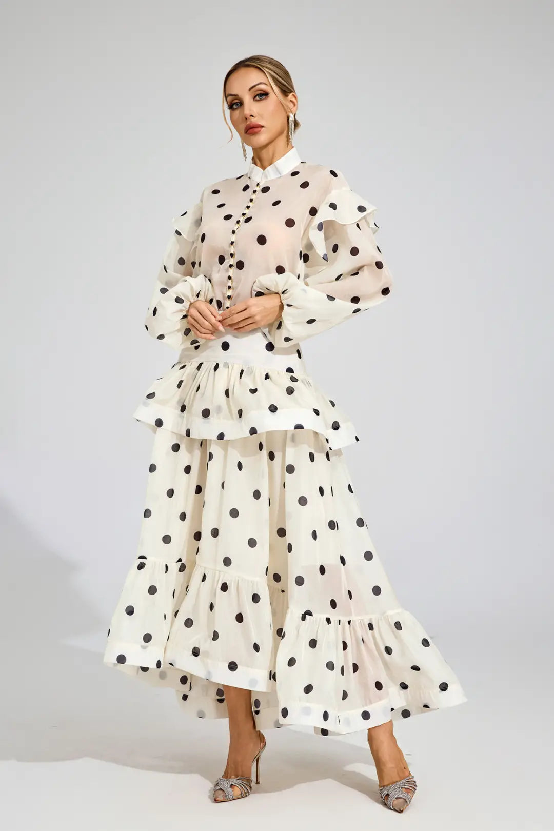Woman wearing a white dress with black polka dots on a plain background